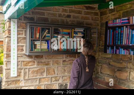 Sedbergh, Main Street, persona nel magazzino dei libri in una ex fermata dell'autobus Foto Stock