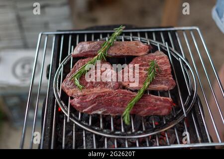 le bistecche di manzo marinate in spezie e le erbe sono grigliate con rosmarino Foto Stock