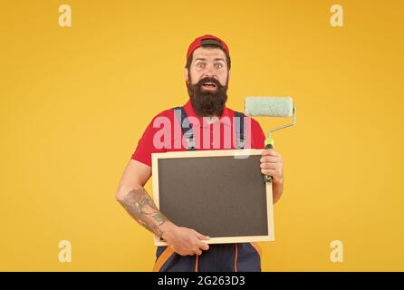 hipster maturo uso rullo di vernice strumento per la pittura. repairman o costruttore di lavoro. idea creativa. caposquadra pubblicizza il servizio di parete di fronte. stupito Foto Stock