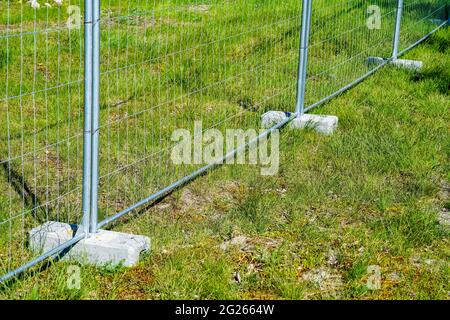 le parti di recinzione in acciaio galvanizzato temporaneo installate in rack per pesi in calcestruzzo mantengono la stabilità della recinzione Foto Stock