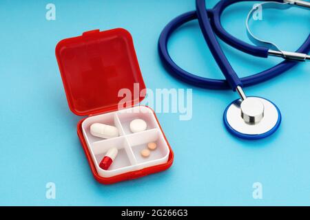 Scatola della pillola giornaliera e stetoscopio su sfondo blu. Concetto di medicina, sanità e farmacia Foto Stock