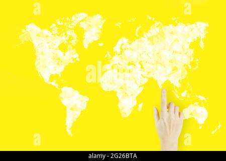 Connessione mappa del mondo in mano. Concetto di connessione globale. Dito della mano della giovane donna che punta con ologramma su sfondo giallo Foto Stock