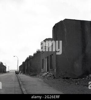 Anni '60, storica, strada desolata con case abbandonate, Kelty, Fife, Scozia, Regno Unito. Un villaggio minerario di carbone al confine tra Fife e Perthshire, in quest'epoca, il villaggio si trovava di fronte a un futuro incerto, poiché le miniere di carbone, che un tempo impiegavano la maggior parte dei lavoratori locali del 1870, quando la prima miniera profonda, la miniera di Lindsey, fu affondata, venivano chiuse o abbandonate. Foto Stock