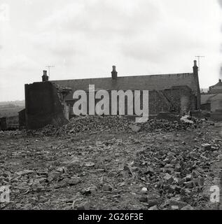 Anni '60 storico, vecchi mattoni, muratura e macerie di costruzione sul terreno dietro un vecchio cottage abbandonato nel villaggio di Kelty, Fife, Scozia, Regno Unito. Un villaggio minerario di carbone al confine tra Fife e Perthshire, in quest'epoca, l'area si trovava di fronte a un futuro incerto, poiché le miniere di carbone, che un tempo avevano impiegato la maggior parte dei lavoratori locali dal 1873, quando la prima miniera profonda, la miniera di Lindsey, fu affondata, venivano chiuse o abbandonate. Foto Stock