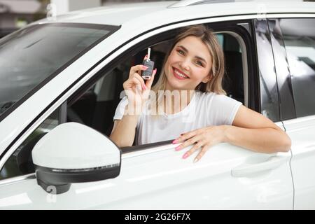 Felice giovane autista che mostra le chiavi dell'auto, seduto in auto Foto Stock