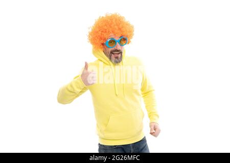 L'uomo divertente indossa funky parrucca capelli con gli occhiali da sole della festa mostrando pollici su gesto della mano, approvazione Foto Stock