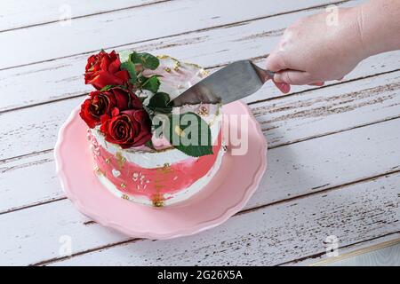 Taglio di una fetta di torta al cioccolato con panna alla meringa svizzera. Foto Stock