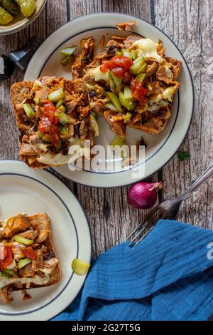 toast alla griglia con carne, formaggio, sottaceti, cipolle smaltate e salsa al barbecue su sfondo rustico e in legno. Vista dall'alto Foto Stock