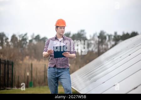 Uomo in casco con piegatrice vicino alla struttura di ingegneria Foto Stock