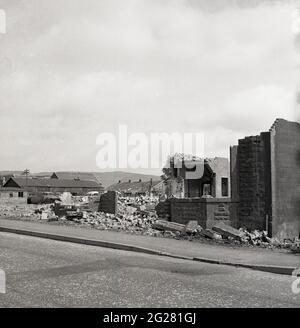 Anni '60 storico, accanto a una strada, macerie e pezzi di muratura sul terreno dalle rovine di abbandonate, vecchie case, Kelty, Fife, Scozia, REGNO UNITO. Un villaggio minerario di carbone al confine tra Fife e Perthshire, in quest'epoca, il villaggio si trovava di fronte a un futuro incerto, poiché le miniere di carbone, che un tempo avevano occupato molte centinaia di lavoratori locali dal 1873, quando la prima miniera profonda, la miniera di Lindsey, fu affondata, venivano chiuse. Foto Stock