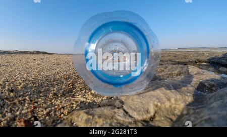 Bottiglia collo primo piano in una giornata di sole sulla spiaggia. Problemi di plastica Foto Stock