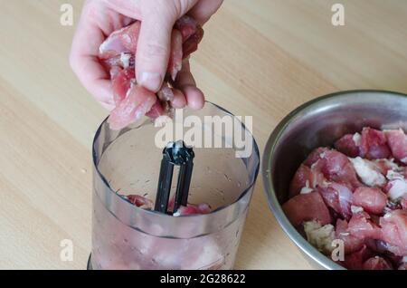 Preparazione graduale del prosciutto tagliato in casa. Fase 3: Parte della carne messa in un miscelatore per fare carne macinata. Maiale tritato. Foto Stock