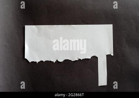 Foglio bianco vuoto con ultima linguetta a strappo su sfondo grigio. Foglio sgualcito. Ultima linguetta di strappo. Concetto di annuncio di strada. Foto Stock