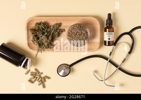Estratto di olio di cannabis, semi di canapa, foglie essiccate e capsule di canapa su sfondo giallo vista dall'alto. Olio cbd di marijuana medica. Trattamento di bellezza alternativo, Foto Stock