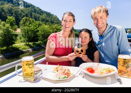 La famiglia felice a pranzo sulla crociera fluviale con bicchieri da birra sul ponte Foto Stock