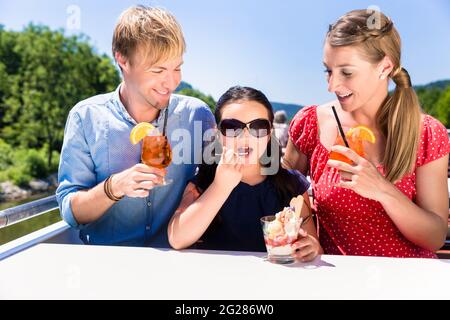 Happy Family a pranzo durante la crociera sul fiume con bicchieri da birra sul ponte Foto Stock