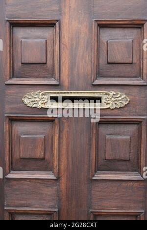 Vista frontale primo piano foto della classica porta in legno con letterbox in ferro ornato. Foto Stock