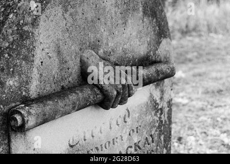 Dettagli atmosferici su una lapide di una mano che tiene un rotolo in bianco e nero con fuoco selettivo Foto Stock