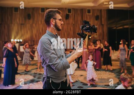 Bel cameraman in occhiali che sparano un matrimonio Foto Stock