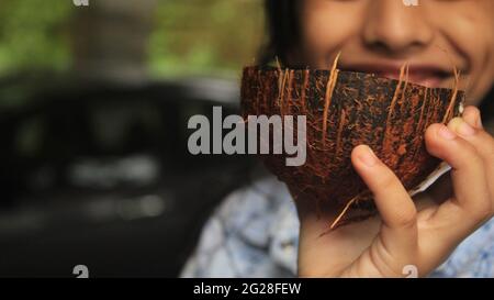 Ragazza che tiene una buccia di cocco con le arachidi crescenti in esso. Foto Stock