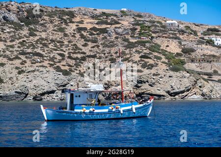 Grecia, isola di Koufonisi. CICLADI. 23 maggio 2021. Barca da pesca ancorata su mare calmo, sfondo roccioso paesaggio. Pescatori che lavorano con le reti. Trad Foto Stock