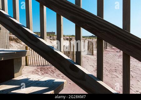 Guardando attraverso la ringhiera di scale di legno che vanno sopra le dune di sabbia a recinzione sulla spiaggia che protegge le dune onn Fire Island New York. Foto Stock