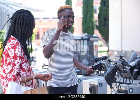 Giovani turisti africani che noleggiano una bicicletta presso un servizio di noleggio biciclette. Concetto di vita cittadina. Foto Stock