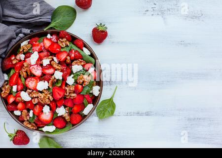 Piatto di un piatto di insalata fresca fatta in casa di foglie di spinaci, fragole a fette, noci, formaggio feta, e un condimento leggero vinaigrette servito Foto Stock