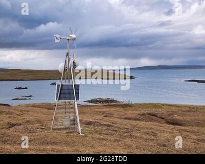 Una stazione di trasmissione dati a microonde alimentata da una turbina eolica e solare sulla brughiera aperta di Lunna Ness, Shetland, Regno Unito Foto Stock