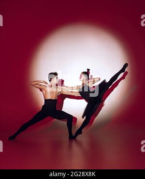 Ballerini balletti che ballano su sfondo rosso dello studio. Design moderno. Luce concettuale colorata e contemporanea come sole nascente al Giappone. Foto Stock