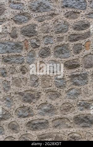 Architettura texture, dettagliate e rustiche di irregolare accoppiato muratura granito mix con piccoli fori, tradizionale... Foto Stock