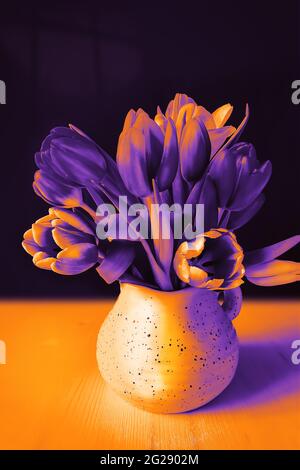 Composizione mistica di duotono con tulipani in una brocca su sfondo nero con luce di luna. Umore di Halloween. Notte, fantasia, fiore ancora vita Foto Stock