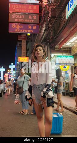 Super modello indossando blusa con le persone sullo sfondo su Yaowarat Road Chinatown Bangkok Thailandia Foto Stock