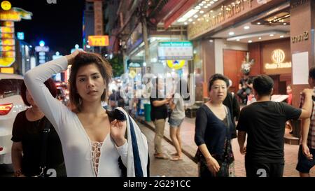 Super modello indossando blusa con le persone sullo sfondo su Yaowarat Road Chinatown Bangkok Thailandia Foto Stock