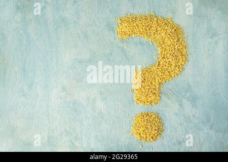 vista dall'alto sul bulgur a forma di punto interrogativo con spazio di copia. couscous su sfondo di legno verde. composizione alimentare o concetto di domande nutrizionali Foto Stock