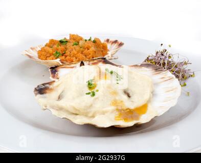 Piatto con due capesante preparate in modo diverso, stile galiziano e con salsa besciamella e olio d'oliva Foto Stock