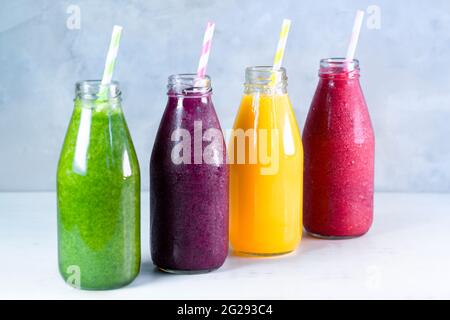 Frullato colorato in bottiglie di vetro. Frullati di frutta estivi in vasetti. Concetto di cibo sano e disintossicante. Foto Stock