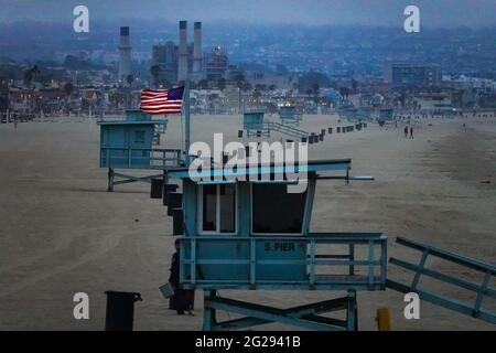 Stazioni di guardia sulla Manhattan Beach nell'area di Los Angeles in una giornata fredda e cupa si siedono abbandonate eccetto che per la bandiera americana che vola orgogliosamente. Foto Stock