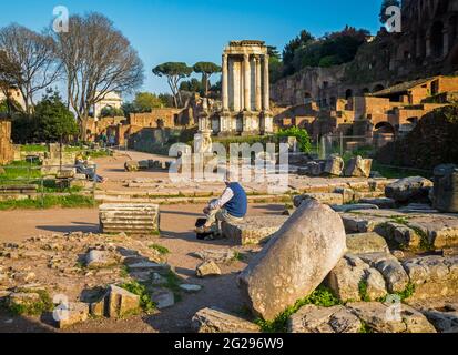 Roma, Italia. Il Foro Romano. I visitatori ammirano il Tempio di Vesta. Arco di Tito (Arco di Tito) sullo sfondo. Il CEN storico Foto Stock