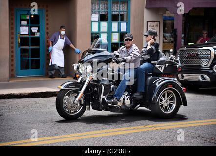 Una coppia anziana guida una motocicletta Harley-Davidson Trike Tri-Glide attraverso la storica piazza di Santa Fe, New Mexico. Foto Stock