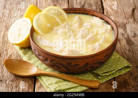 Zuppa di pollo greco, riso e limone fatta in casa Kotosoupa Avgolemono primo piano in una ciotola sul tavolo. Orizzontale Foto Stock