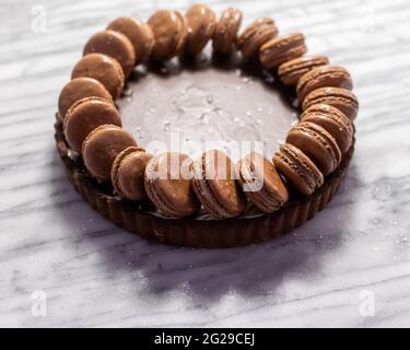 Torta al caramello salato al cioccolato fondente con macaron Foto Stock