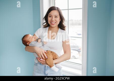 Festa della mamma. Orgogliosa madre cinese asiatica con neonato bambino. Foto Stock