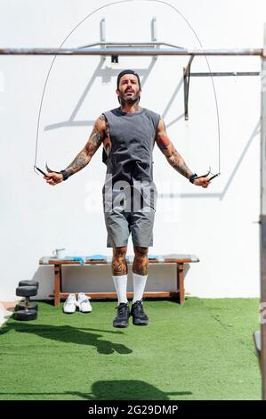 L'uomo muscolare saltellando l'esercizio con corda saltante in palestra Foto Stock
