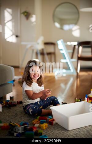 Ritratto di ragazza carina sorridente mentre si gioca con i giocattoli a casa Foto Stock