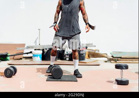 Allestitore non riconoscibile che esegue sollevamenti a vuoto pesanti Foto Stock
