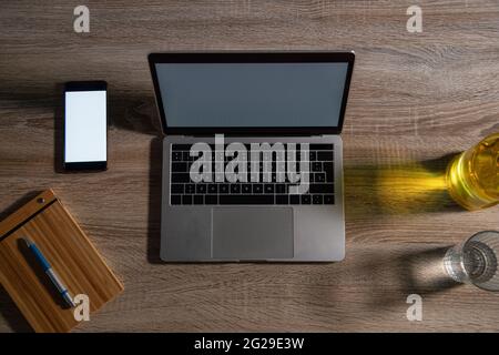 Vista dall'alto del computer portatile e dello smartphone su un tavolo in legno in ufficio Foto Stock