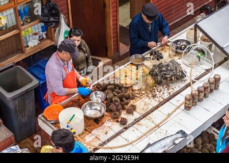 PUERTO MONTT, CILE - 1 MARZO 2015: I venditori preparano cozze e ricci di mare al mercato del pesce di Puerto Montt, Cile Foto Stock