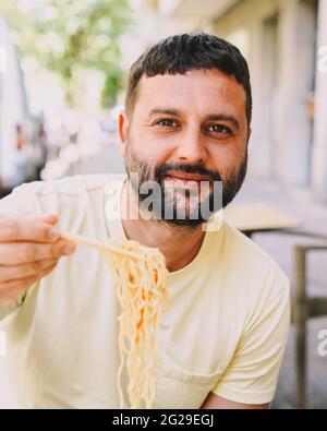 Ragazzo latino in t-shirt gialla che mangia cibo giapponese Foto Stock