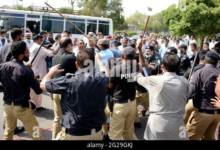 Il personale della polizia ripristina la carica di testimone e i dimostranti di arresto per respingere mentre si spostano verso l'area della Red zone durante la dimostrazione di protesta della Government Secondary Teachers Association per il miglioramento dello stipendio, l'emissione di carte sanitarie e altre richieste, vicino Shaheen Complex a Karachi Mercoledì 09 giugno 2021. Foto Stock